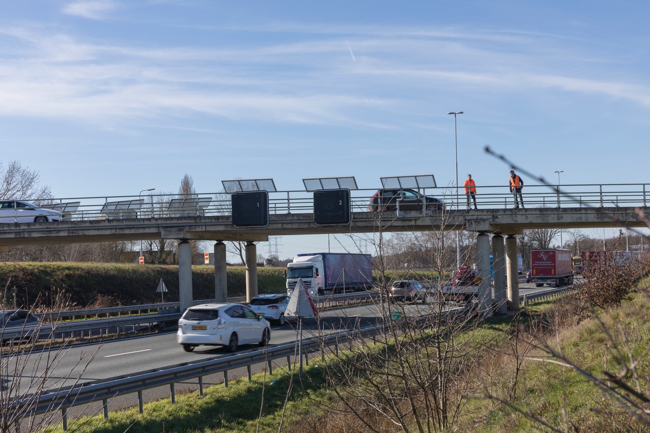 Foto van auto's op de A58 bij een viaduct met werklui