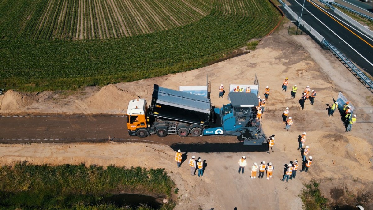 luchtfoto van asfaltspreidmachine met mensen die eromheen staan